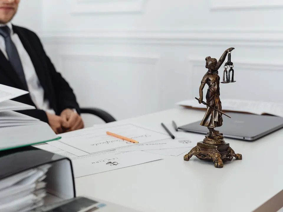 Bureau op een advocatenkantoor met dossiermappen, documenten en een beeldje van vrouwe Justitia