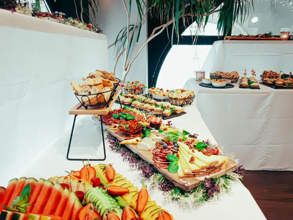 Cateringbuffet met broodjes, kaas, vleeswaren en fruit op tafels met witte kleden