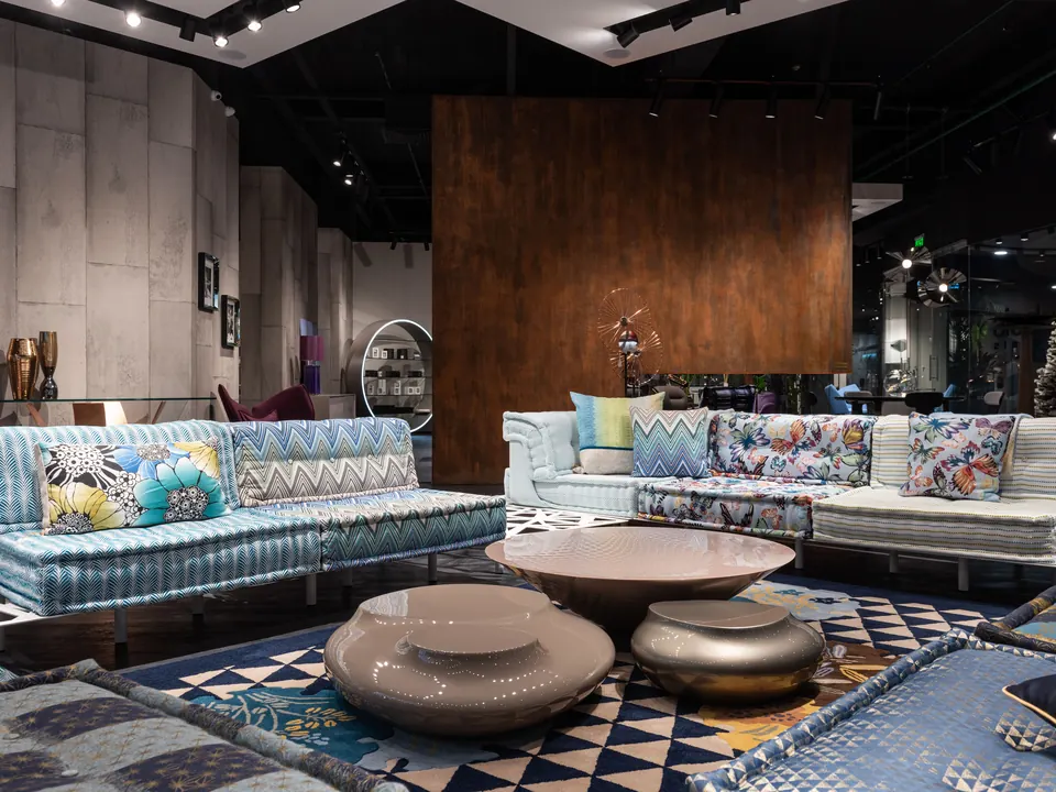 Showroom met bankelementen met kleurrijke kussens, lage salontafels en een patroonkleed